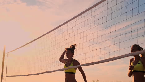 Group-of-young-girls-playing-beach-volleyball-during-sunset-or-sunrise